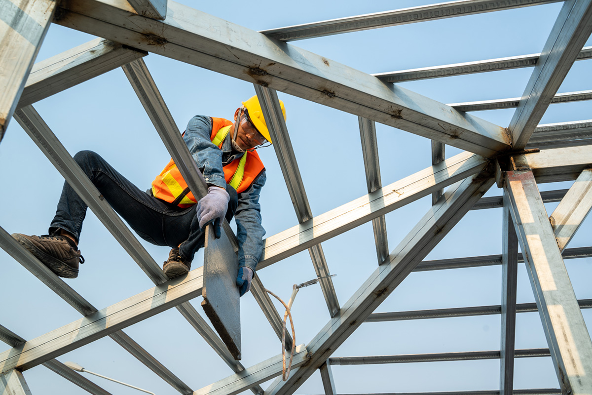 Photo of a construction worker wearing safety harness working in a high place.