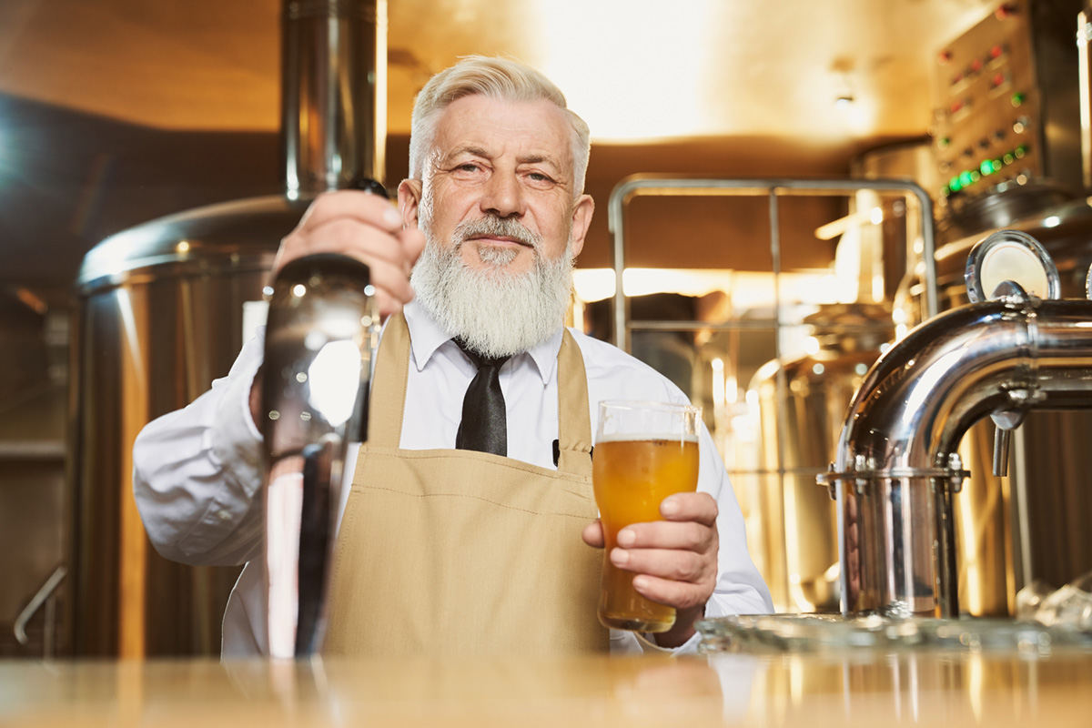 A brew master holding a beer at a brewery.