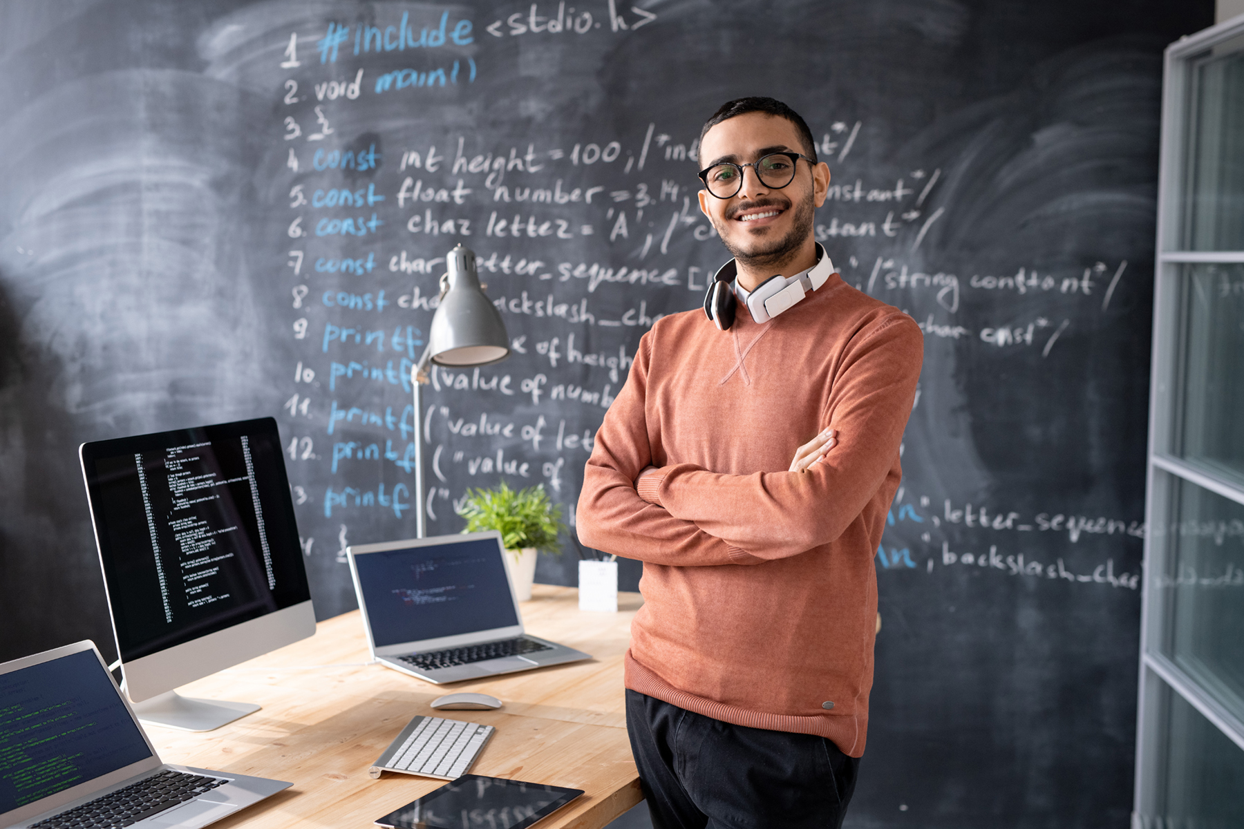 Young IT manager posing in front of a desk and laptop.